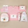 Un juego de regalo personalizado para una niña, de color rosa, con babi, tapper, pegatinas, botella y mochilas.