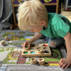 Un joven niño jugando con juguetes de madera en el suelo, un rompecabezas de Louisa Puller, tendencia en Pinterest, movimiento de artes y artesanías, pixel perfecto, captura de pantalla de PlayStation 5, patrón repetitivo.