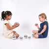 Dos pequeñas niñas sentadas en el suelo jugando con pelotas, una foto de stock de Yayoi Kusama, presentada en dribble, arte cinético, trazado de rayos, fotografía de estudio, hecha de metal líquido.
