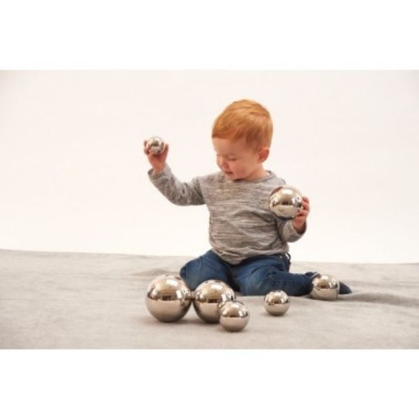 Un pequeño niño sentado en el suelo jugando con algunas pelotas, una foto de stock de Cornelia Parker, tendencia en Shutterstock, Fluxus, trazado de rayos, fotografía de estudio, foto de stock.