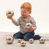 Un niño pequeño sentado en el piso jugando con bolas de plata, una foto de stock de Anne Geddes, tendencia en Pinterest, arte cinético, trazado de rayos, foto de stock, hecha de metal líquido
