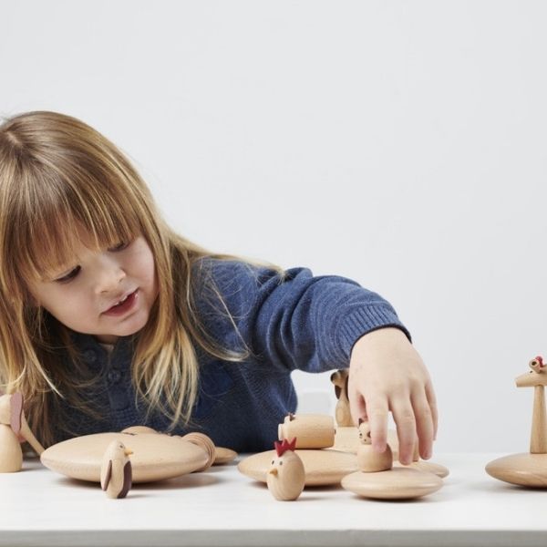 Una niña pequeña jugando con juguetes de madera sobre una mesa, un rompecabezas de Sophie Taeuber-Arp, destacado en dribble, figurativismo, patrón repetitivo, fotografía de estudio, trazado de rayos.