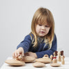 Una pequeña niña jugando con juguetes de madera en una mesa, una escultura abstracta de Sophie Taeuber-Arp, destacada en la bola de nieve, arte cinético, hecho de cartón, patrón repetitivo, skeuomórfico.