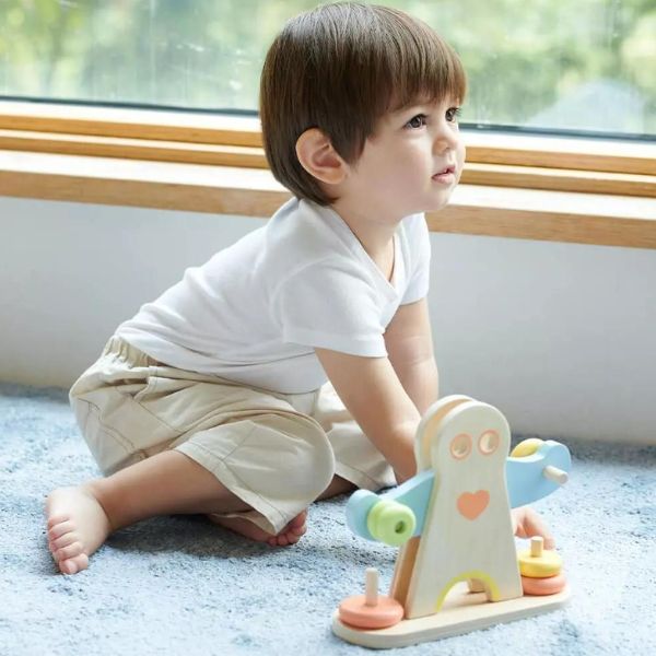 Un niño pequeño jugando con un juguete frente a una ventana, una escultura abstracta de Cicely Hey, presentada en Dribble, neoismo, escultura de mármol atractiva, sin género.