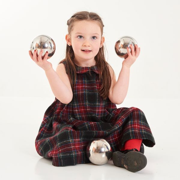 Una niña pequeña sentada en el suelo sosteniendo dos pelotas, un retrato de personaje de Annie Abernethie Pirie Quibell, presentado en cg society, arte cinético, fotografía de estudio, retrato de estudio, trazado de rayos.