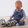Load image into Gallery viewer, Un bebé sentado en el suelo jugando con tres bolas de metal, una escultura abstracta de Anne Geddes, de tendencia en Shutterstock, arte cinético, trazado de rayos, fotografía de estudio, fotografía de stock.