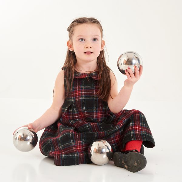 Una pequeña niña sentada en el suelo sosteniendo dos pelotas, un retrato de carácter de Annie Abernethie Pirie Quibell, presentado en cg society, arte cinético, fotografía de estudio, retrato de estudio, iluminación de estudio.