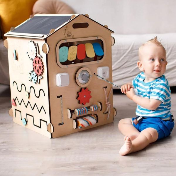 Un bebé sentado en el suelo al lado de una casa de cartón, un dibujo de un niño hecho por Eden Box, tendencia en Pinterest, los automatistas, Adafruit, hecha de cartón, circuitos.