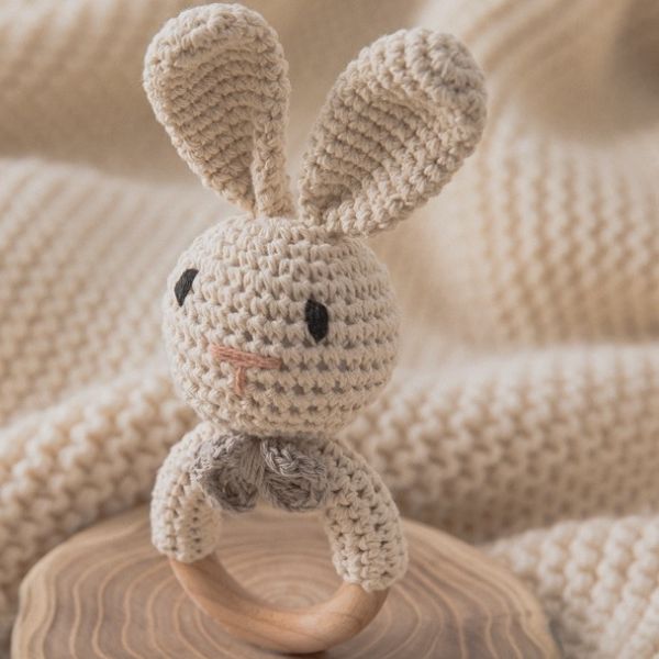 Un conejo tejido a ganchillo sentado sobre un anillo de madera, un bordado en punto cruzado por Nyuju Stumpy Brown, tendencia en Pinterest, movimiento de artesanía hecho con cuentas y hilo, Adafruit, profundidad de campo poco profunda.