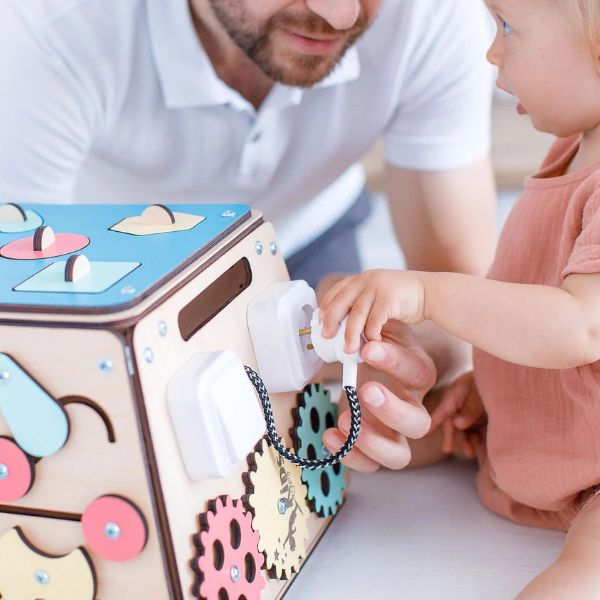 Un hombre y un niño jugando con un juguete, un rompecabezas de Eden Box, presentado en Dribble, Los Automatistas, Adafruit, Skeuomórfico, Tecnología Futura.