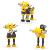 Un conjunto de tres figuras de robots amarillo y negro, un rompecabezas de Rube Goldberg, destacado en dribble, los automatistas, hecho de caucho, filtro Sabattier, fotografía de estudio.