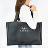 Una mujer está sosteniendo una bolsa negra con un nombre en ella, una renderización digital de Laura Ford, ganadora del concurso de Pinterest, estilo tipográfico internacional, pixel perfecto, #myportfolio, photoillustration.