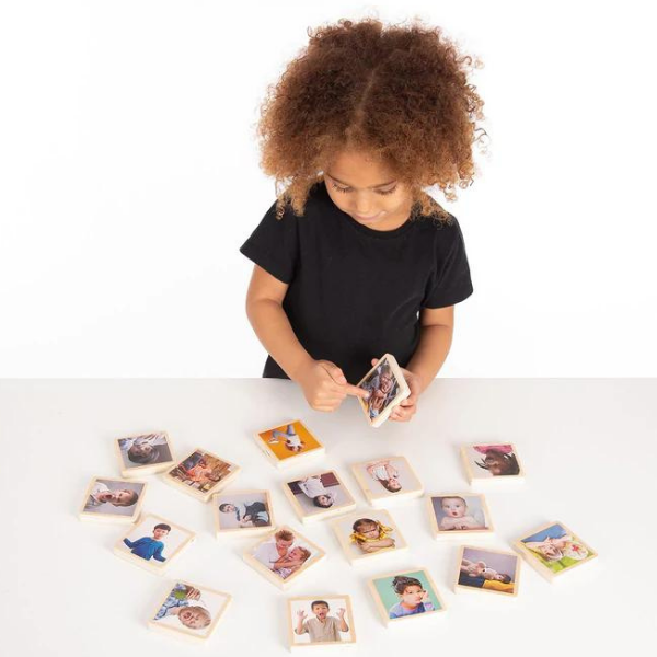 Una pequeña niña sentada en una mesa jugando con fotos, un rompecabezas de Keren Katz, ganador de un concurso de Pinterest, ensamblaje, fotografía de estudio, foto de stock, foto de stock.