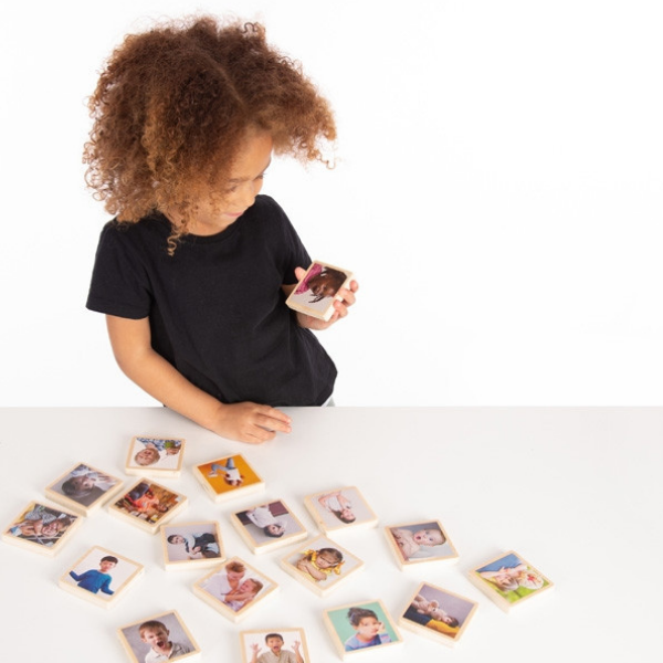 Una pequeña niña sentada en una mesa con un montón de fotos, un rompecabezas de Harriet Zeitlin, ganadora del concurso de Shutterstock, ensamblaje, foto de stock, foto de stock, fotografía de estudio.