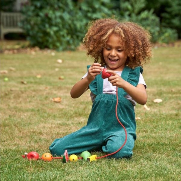 Una pequeña niña sentada en la hierba jugando con un juguete, un punto de cruz por Annabel Kidston, ganador del concurso de Instagram, movimiento de artesanía y artes, perfecto pixel, dibujo de un niño, obra de arte.