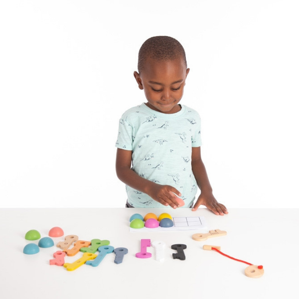 Un joven niño jugando con letras y números de madera, una foto de stock de Ben Enwonwu, destacada en dribble, ensamblaje, patrón repetitivo, adafruit, fotografía de estudio.