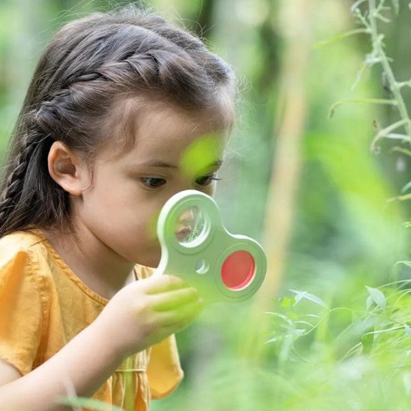Una niña pequeña mirando a través de una lupa, una foto de stock de Anne Geddes, ganadora de Shutterstock Contest, arte ambiental, destello de lente anamórfica, stockphoto, enfoque nítido.