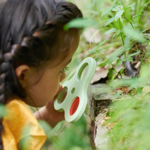 Una pequeña niña mirando un objeto en forma de mariposa, una foto de stock por Hilda Annetta Walker, ganadora del concurso de Shutterstock, Escuela de Heidelberg, profundidad de campo superficial, profundidad de campo, enfoque nítido.