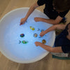 Dos niños jugando con imanes en una bañera, un holograma de Jeff Koons, presentado en dribble, arte interactivo, bioluminiscencia, luminiscencia, iluminación volumétrica.