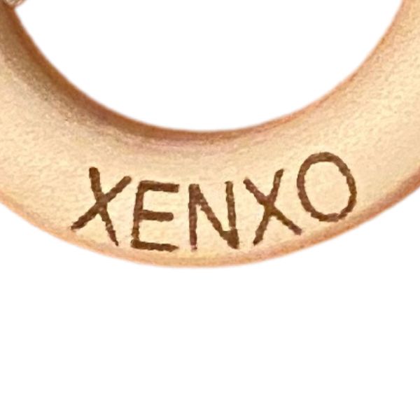 Una toma cercana de un anillo con la palabra Xenxo escrita en él, un tatuaje de Wolfgang Zelmer, ganador del concurso de Instagram, estilo tipográfico internacional, alto detalle, logotipo, lente macro.