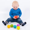 Una bebé sentada en el piso jugando con las bolas, una foto de stock de Keos Masons, destacada en Shutterstock, neo-fauvismo, foto de stock, fotografía de estudio, foto de stock.