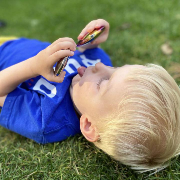 Una joven niño tumbado en la hierba jugando con un teléfono celular, una foto de stock de Louisa Puller, ganador del concurso de Instagram, superplano, foto tomada con Nikon D750, foto de stock, ganador del concurso.