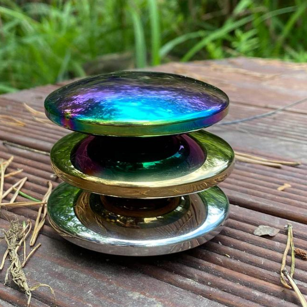 Un objeto de vidrio colorido sentado en la parte superior de una mesa de madera, una escultura abstracta por Unkoku Togan, ganador del concurso de Instagram, holografía, iridiscente, holográfico, brillante.
