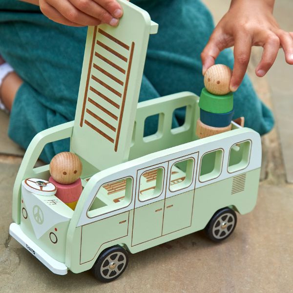 Una niña jugando con un autobús de juguete de madera, una ilustración de cuento de Annabel Kidston, presentado en dribble, movimiento de artes y artesanías, hecho de cartón, fantasioso, ilustración de cuento.