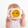 Load image into Gallery viewer, Una bebé sosteniendo un juguete de madera con una cara amarilla, una foto de stock por Anne Geddes, ganadora del concurso de Behance, arte conceptual, fotografía de estudio, Behance HD, filtro anaglifo.